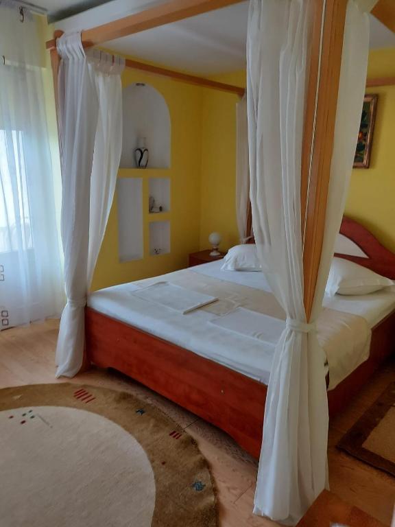 a bedroom with two beds with white drapes at Casa Belu in Eforie Nord
