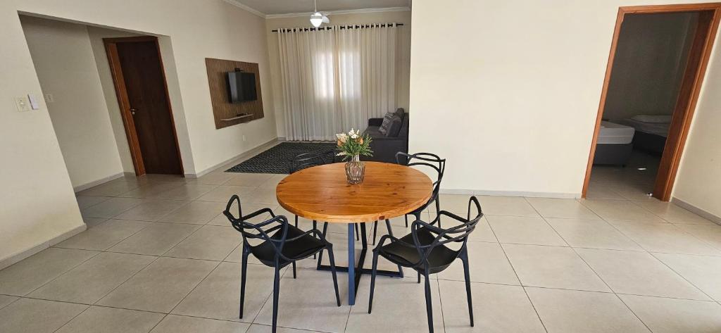 a wooden table with chairs and a vase with flowers on it at Apartamento da Dani in Guaratinguetá