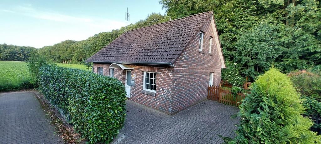 a small brick building with a fence and trees at "Am Waldesrand" RE16 in Sögel