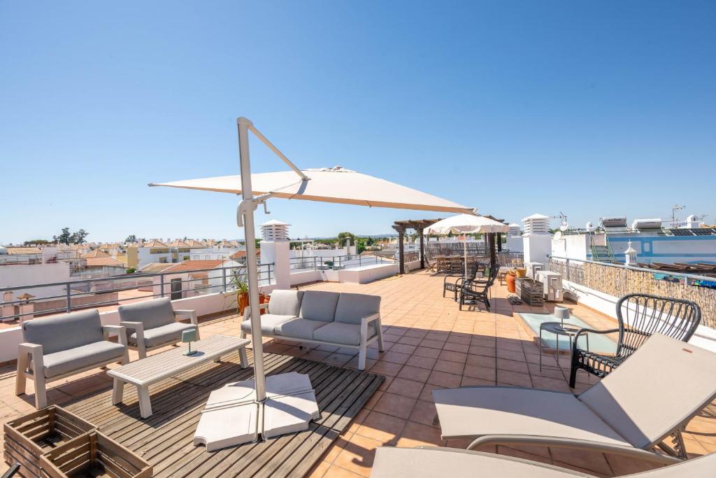 a patio with chairs and an umbrella on a roof at Rivara Rooftop By ALGARTUR in Cabanas de Tavira