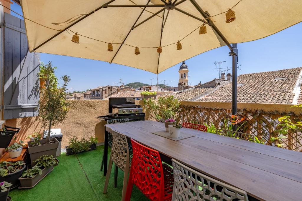 a patio with a wooden table and an umbrella at La Terrasse de Vidauban - Duplexe climatisé in Vidauban