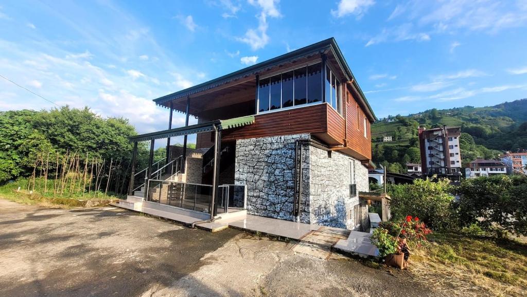 a small house with glass windows on a hill at Umut Konaklama in Ardeşen
