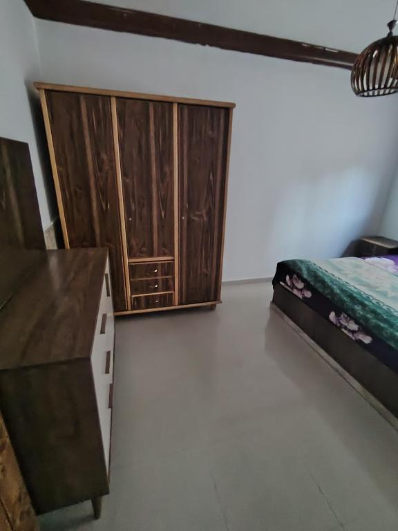 a bedroom with a bed and a wooden cabinet at شقة سرايا in Irbid