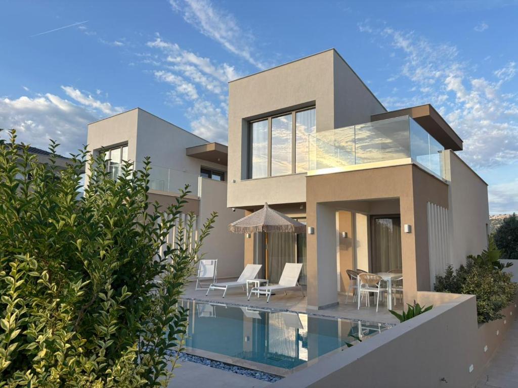 a house with a swimming pool in front of it at Calm Luxury Villas in Limenaria