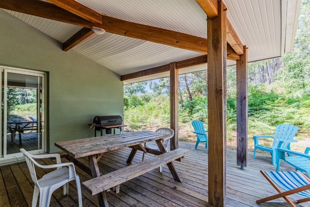 a wooden porch with a picnic table and chairs at Appartement 6 p Sanguinet-"Chott" in Sanguinet