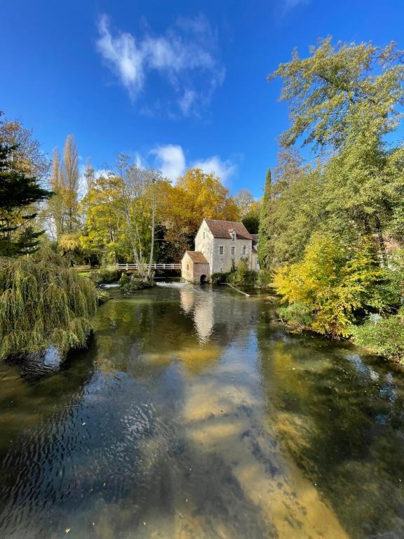 a river with a building in the middle of it at Moulin Dorceau - 15 couchages - voir notre site in Rémalard