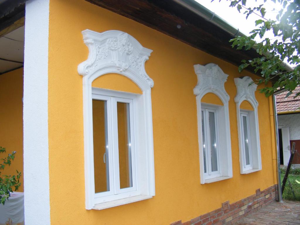 three windows on the side of a yellow house at Négy Gólya in Sarud