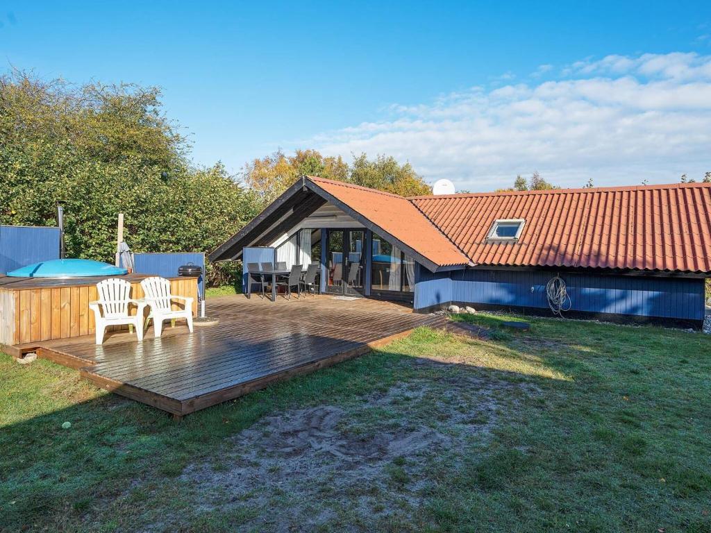 a wooden deck with two chairs and a house at 5 person holiday home in Dannemare in Dannemare