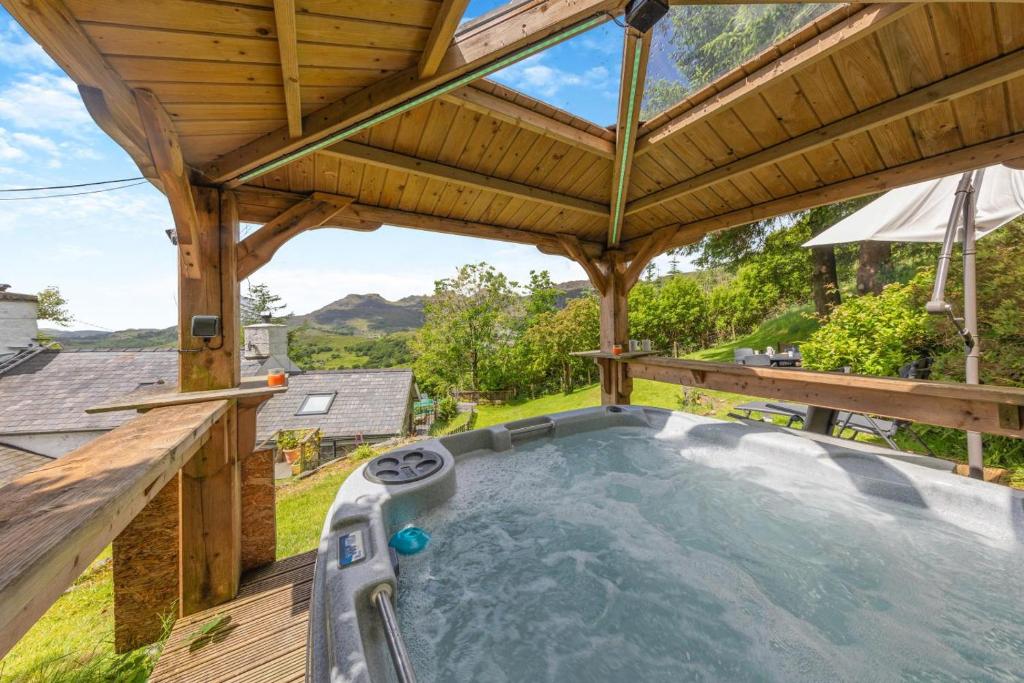 an outdoor hot tub in a wooden deck with a wooden roof at 3 Bed in Fucheswen oc-m29608 in Blaenau-Ffestiniog