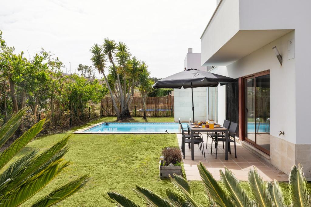 a patio with a table and umbrella next to a pool at Vila Moleza in Vau
