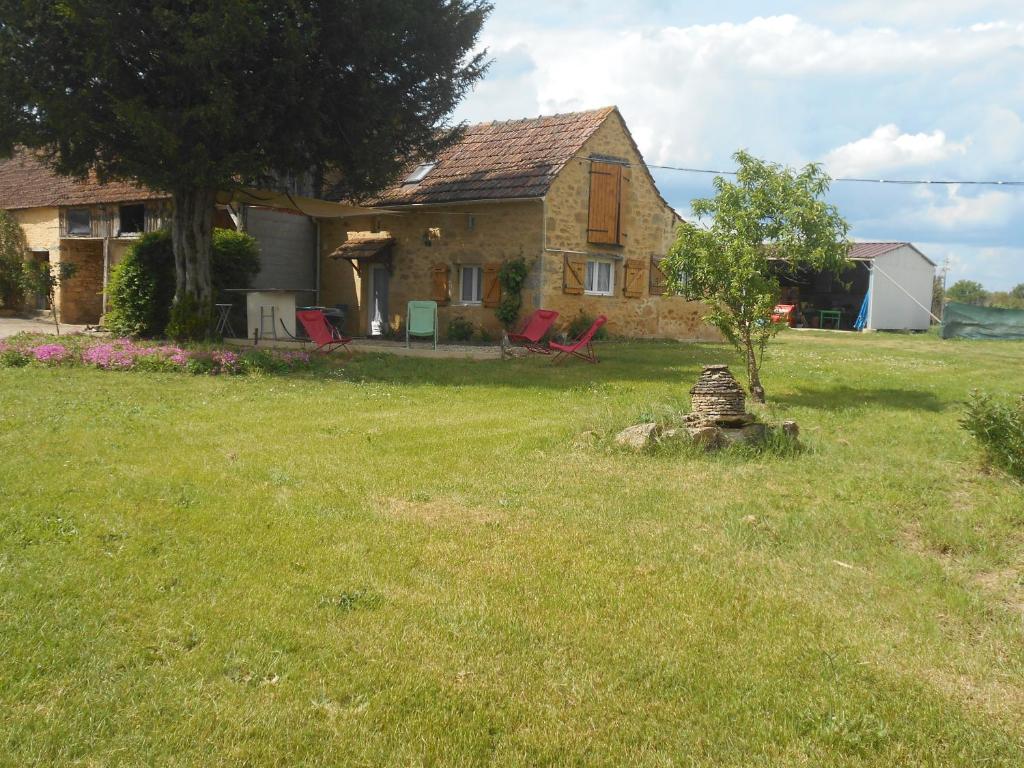 a house with a yard with a tree and chairs at gite a la ferme in Milhac