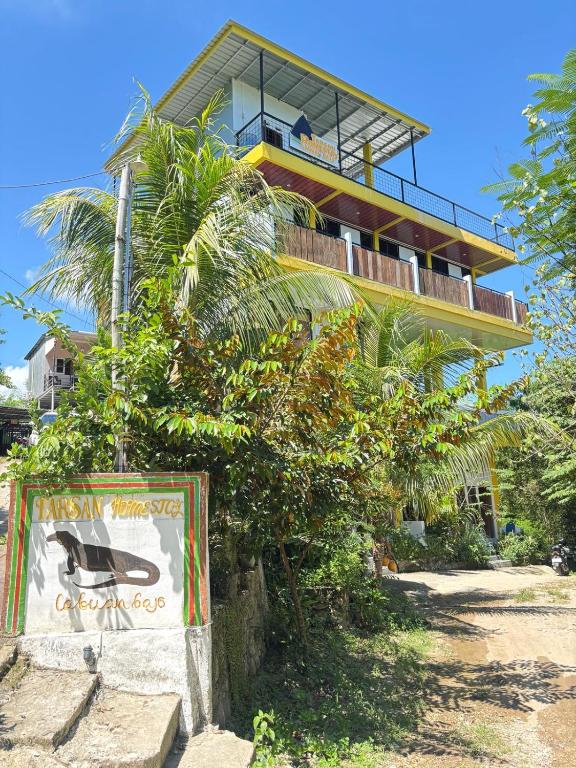 a house on the beach with a sign in front of it at Tarsan Homestay in Labuan Bajo