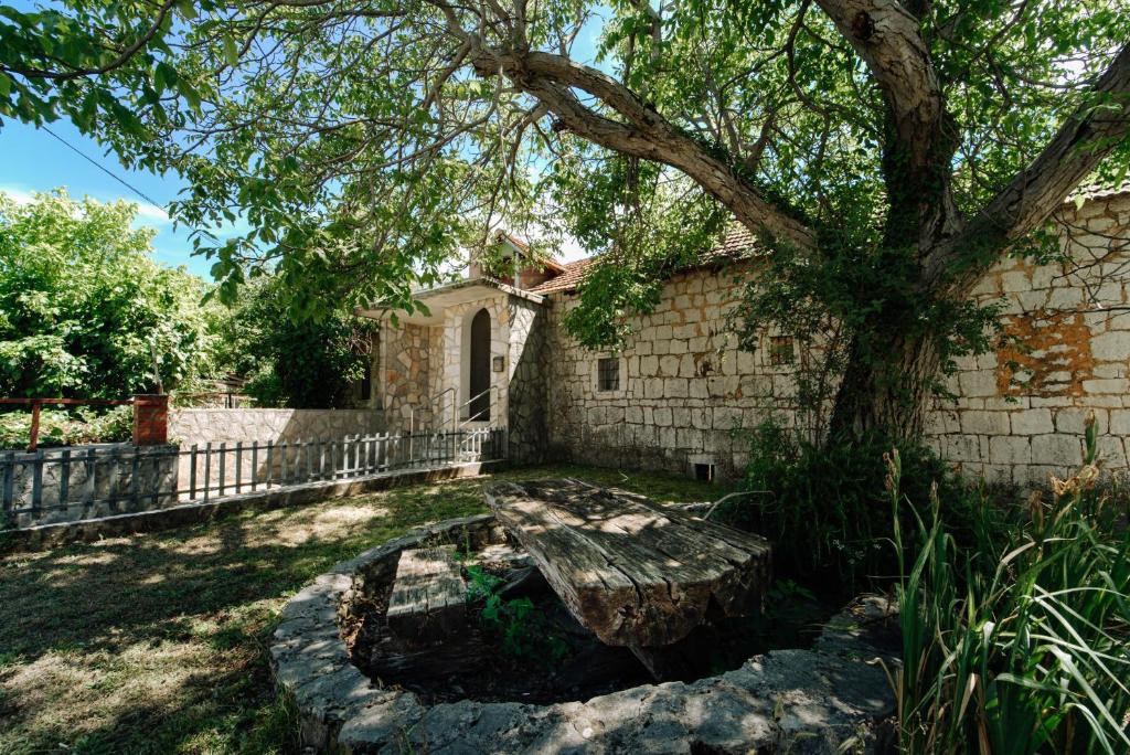 a tree and a bench in front of a building at Izba Vacation Home in Međugorje