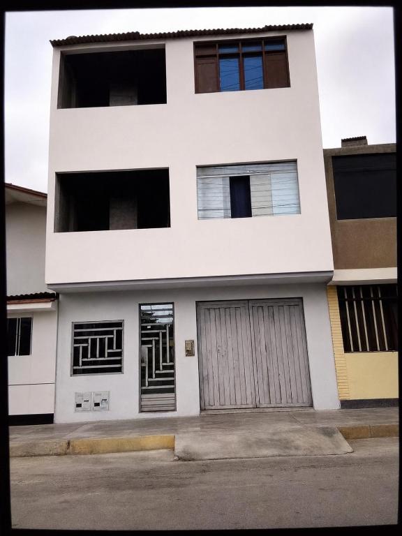 a white apartment building with two garage doors at La Partillana in Chimbote