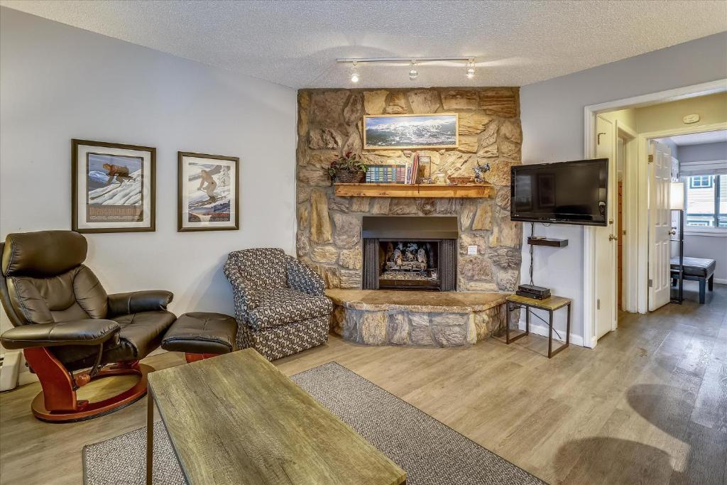 a living room with a stone fireplace and a tv at Tannhauser 313 in Breckenridge
