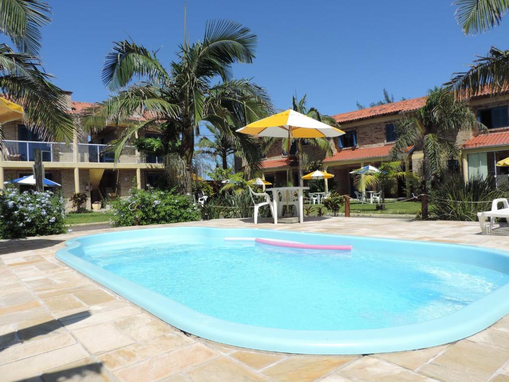 uma grande piscina com um guarda-sol e uma casa em Pousada Don Fernandes em Torres