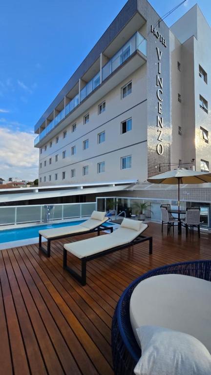 a hotel with two beds and a pool on a deck at Vincenzo Hotel in São Vicente de Minas