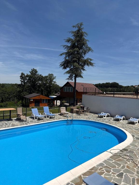 a large blue swimming pool with chairs and a house at Kosmaj Thalia in Babe