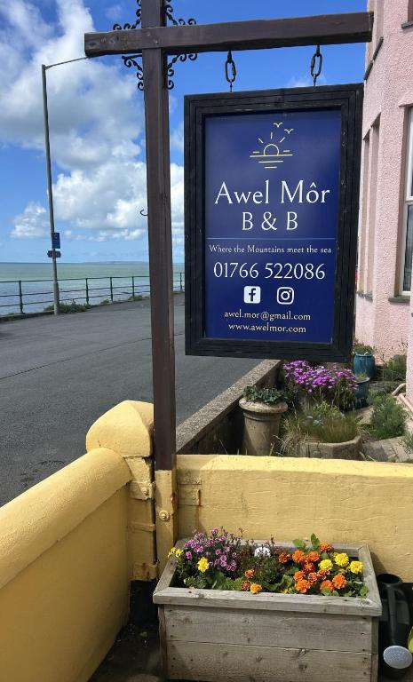 a sign for a flower garden next to a street at Awel Mor in Criccieth