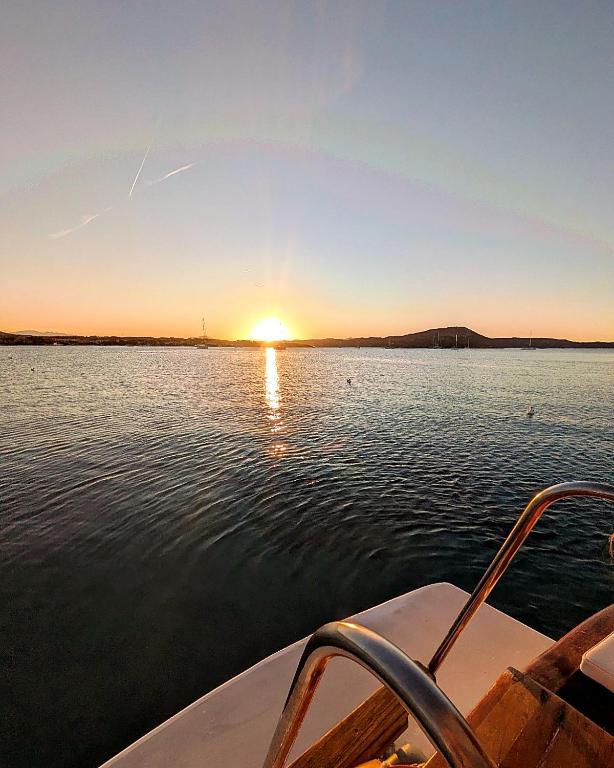 a boat on a lake with the sun setting at Che Manovra - A Night Onboard! in Porto San Paolo