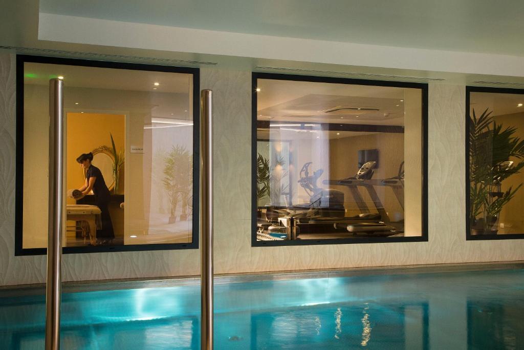 a swimming pool in a house with three windows at Hôtel & SPA Oceania L'Univers Tours in Tours