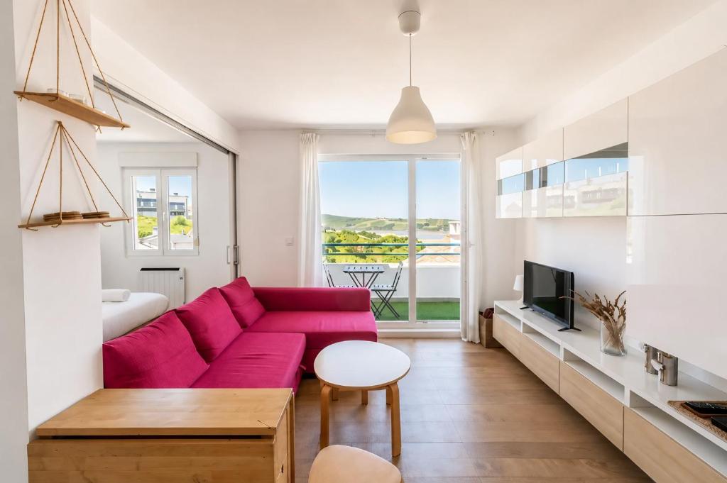 a living room with a red couch and a tv at Brisa de Usil in Mogro