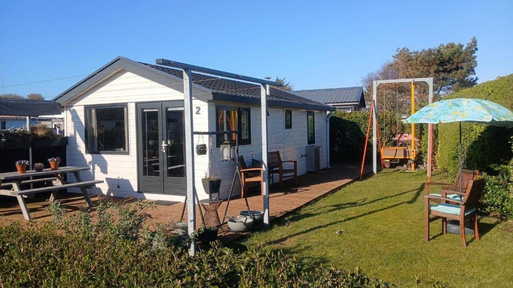 a small white house with a table and an umbrella at Sunny Side at the Sea in Hoek van Holland