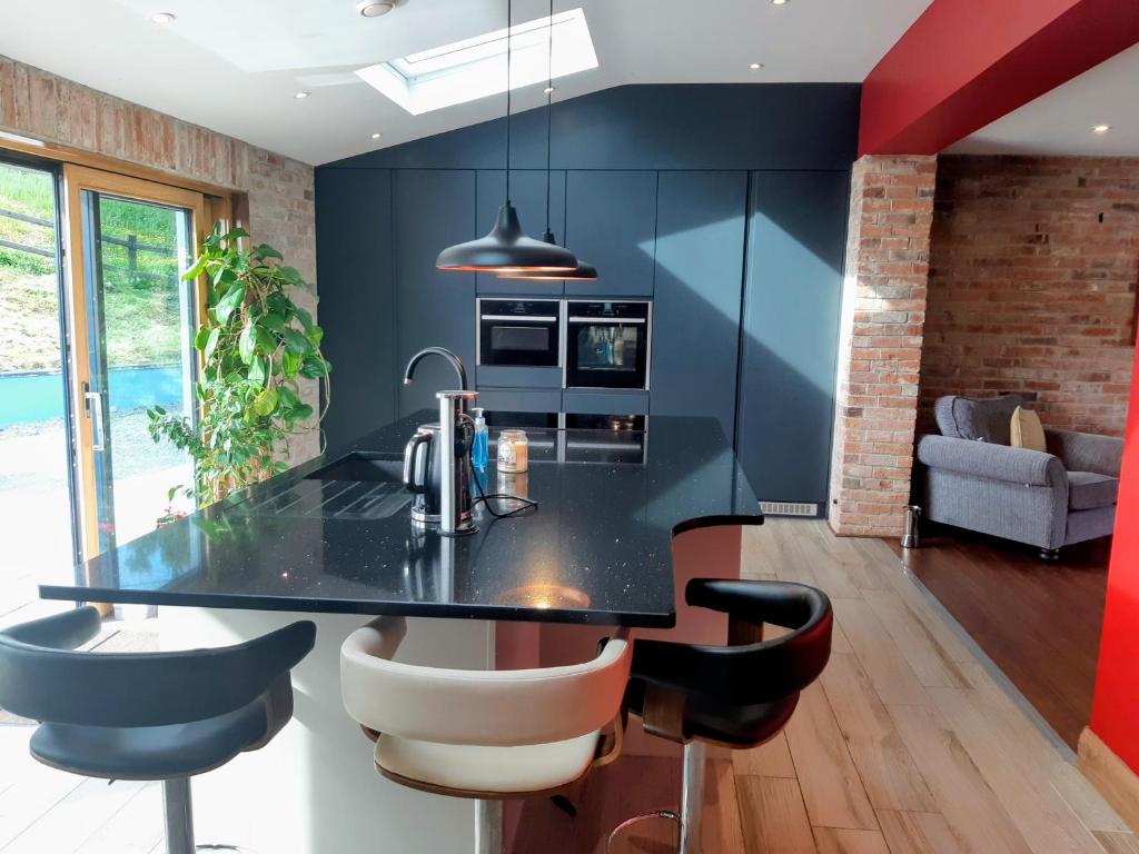 a kitchen with a black counter and some chairs at Golf Style in Lisdoonvarna
