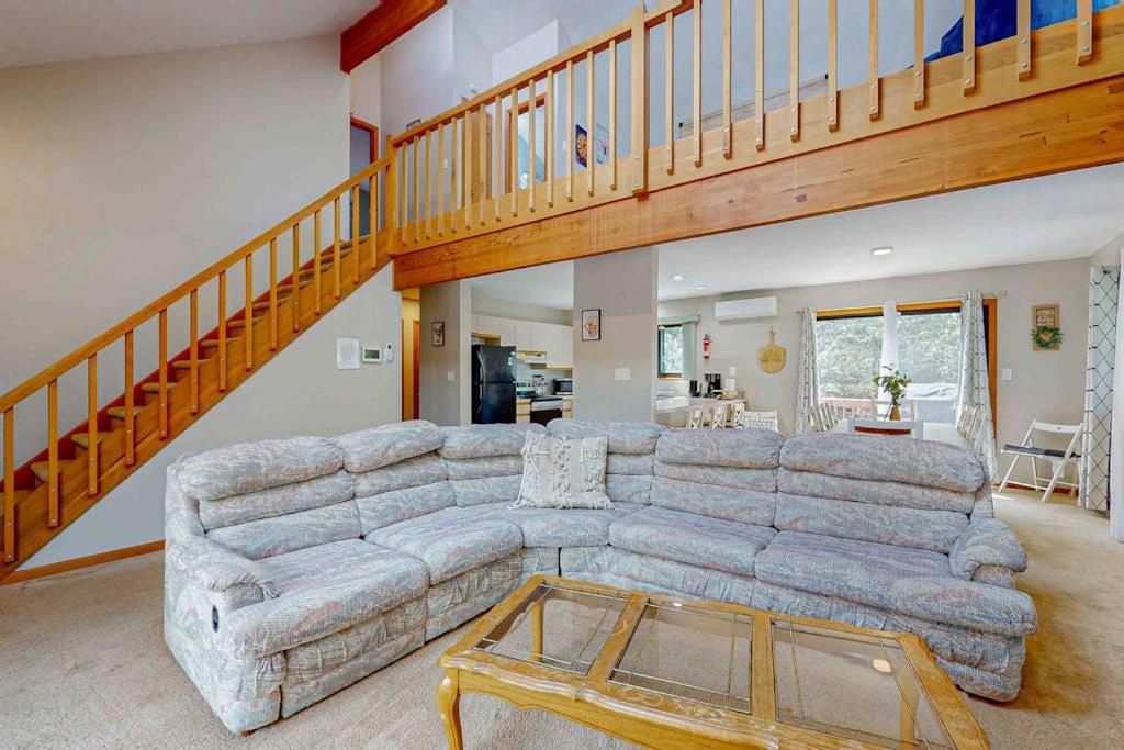 a living room with a sectional couch and a staircase at House in the Woods in Albrightsville