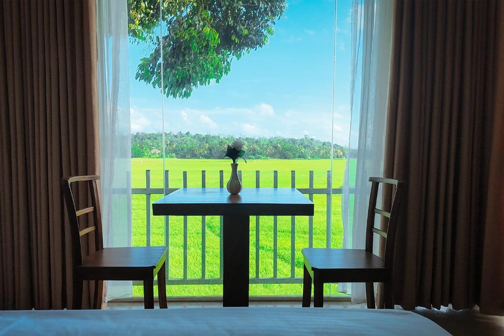 a table and two chairs in front of a window at Nil Nadiya Holiday Resort in Matara