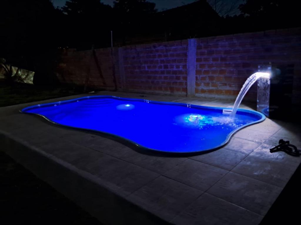 a blue swimming pool with a water fountain at night at Quinta Sinaí in Encarnación