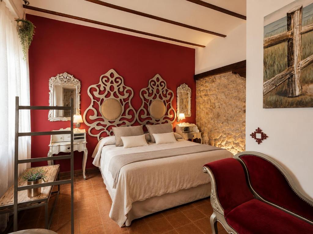 a bedroom with a large bed and a red wall at RETIRO DEL TEATRO Hotel Boutique y Apartamentos en Almagro in Almagro