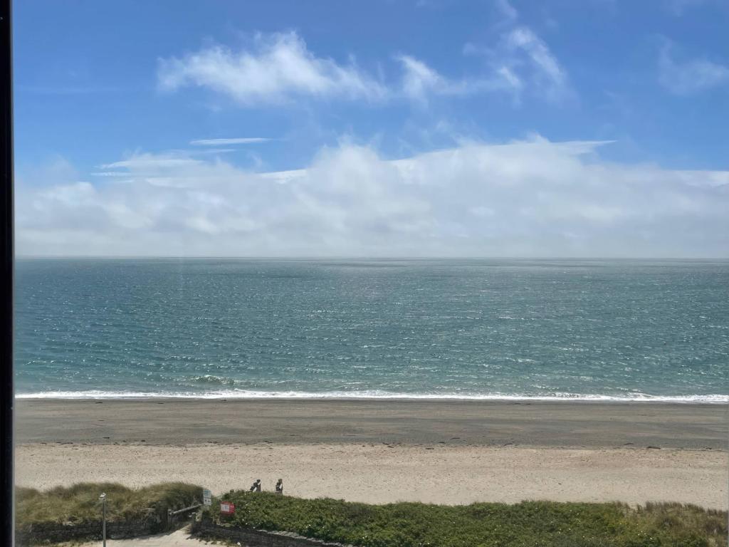 a beach with people standing on the sand and the ocean at Snowdonia View in Pwllheli