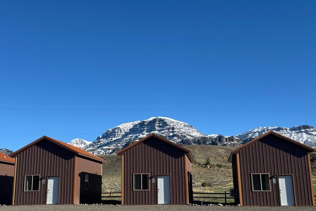 three buildings with snow covered mountains in the background at Old Faithful RV Park LLC in Cody