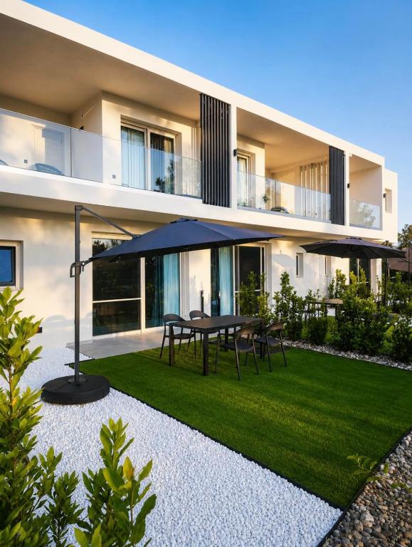 a house with a patio with a table and umbrella at Ammos Maisonettes in Pefkari