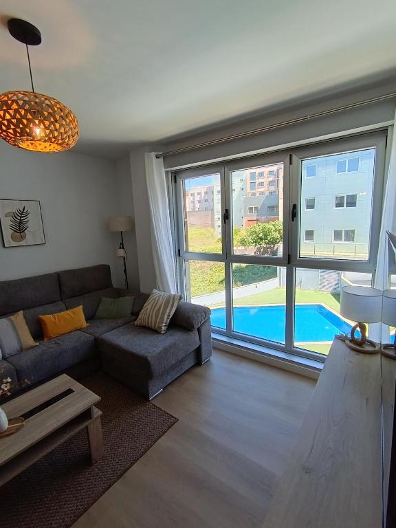 a living room with a couch and a large window at Las gaviotas,playa,piscinayparking in Malpica