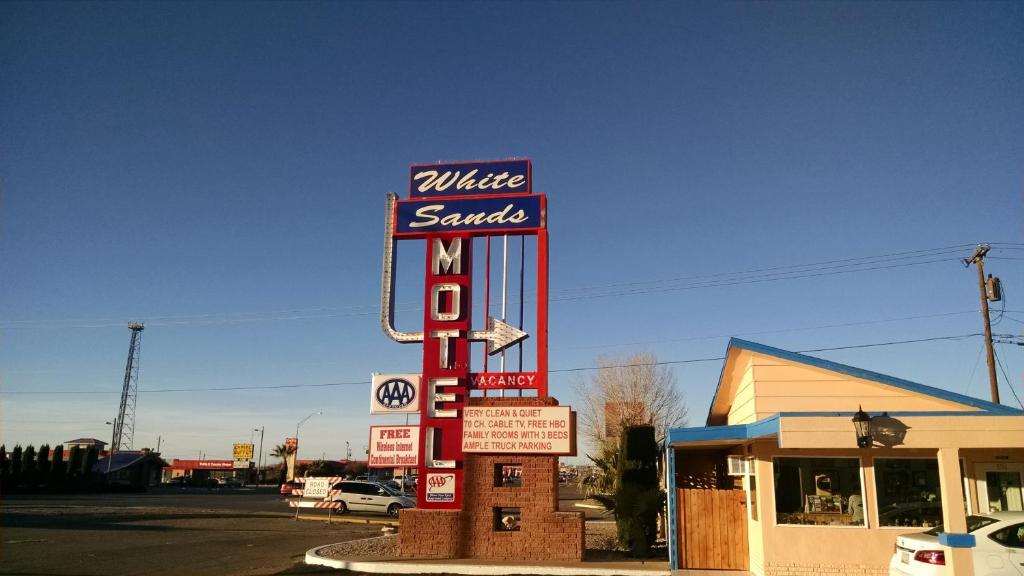 a large motel sign in front of a gas station at White Sands Motel in Alamogordo