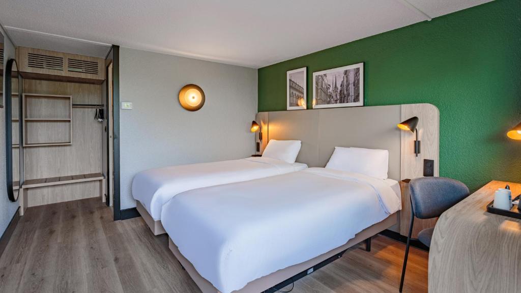 a hotel room with two beds and a green wall at Campanile NATURE - Poitiers Sud Aeroport in Poitiers