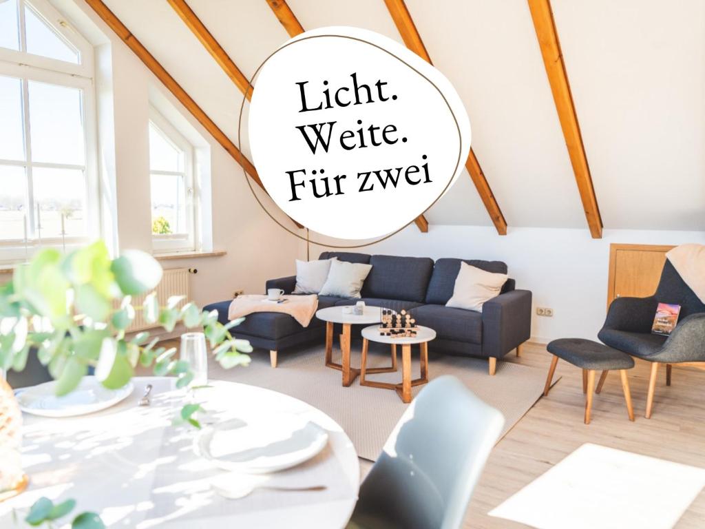 a living room with a blue couch and chairs and a table at Huus Binnensee OG2 - Dachwohnung mit Wasserblick - Lesesessel & WLAN - Für Paare - Ruhige Lage - Südstrand 5 Min mit Rad in Fehmarn