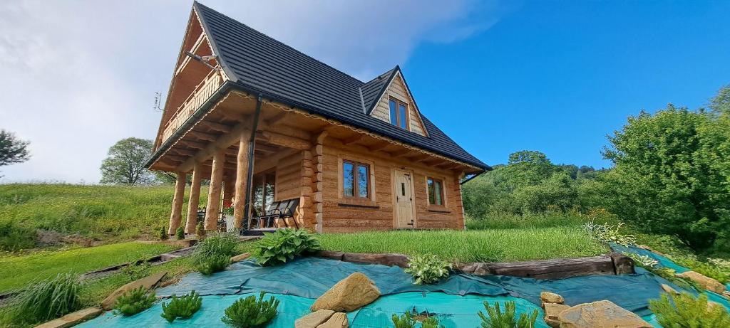 a log cabin with a pond in front of it at Dom na wyłączność U Eskulapa in Lutowiska