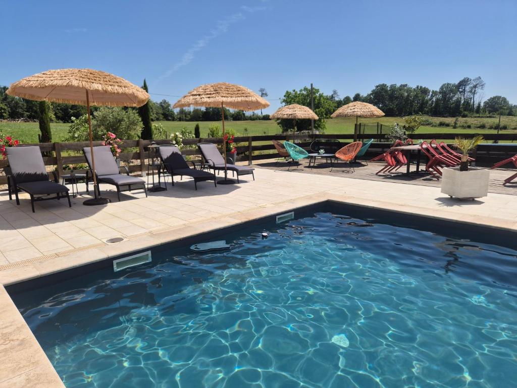 a swimming pool with chairs and tables and umbrellas at Chambres D'hôtes Bien-être Simple in Belvès