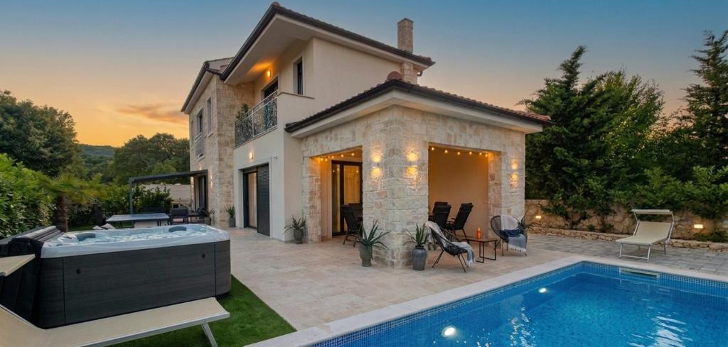a villa with a swimming pool in front of a house at Luxury Villa Aramis with jacuzzi in Malinska in Sveti Ivan