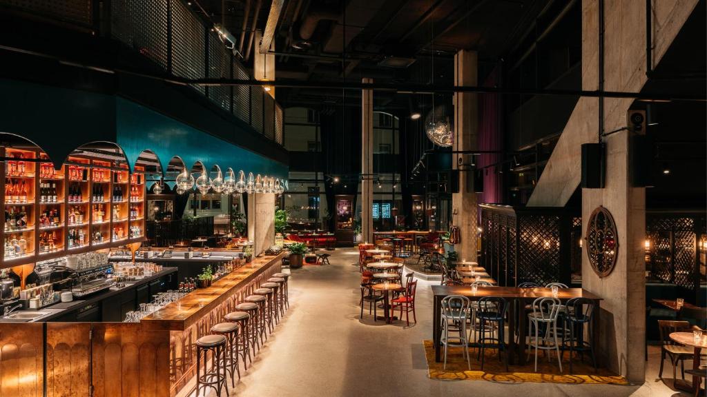a restaurant with wooden tables and chairs in a building at Ruby Hanna Hotel Stuttgart by IHG in Stuttgart