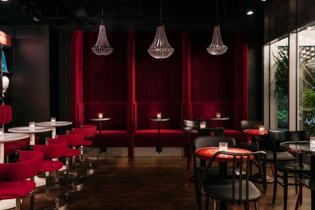 ein Restaurant mit roten Wänden, Tischen und Stühlen in der Unterkunft Ruby Leni Hotel Dusseldorf by IHG in Düsseldorf