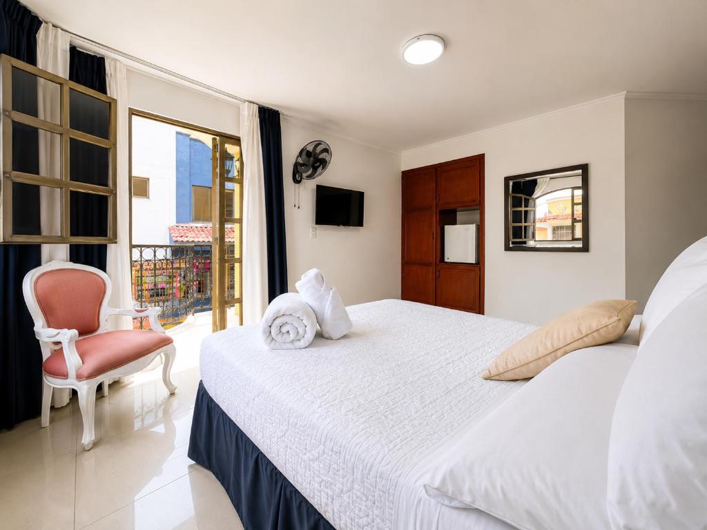 a bedroom with a bed and a chair and a window at Hotel Suite Santa Rosa in Santa Rosa de Cabal