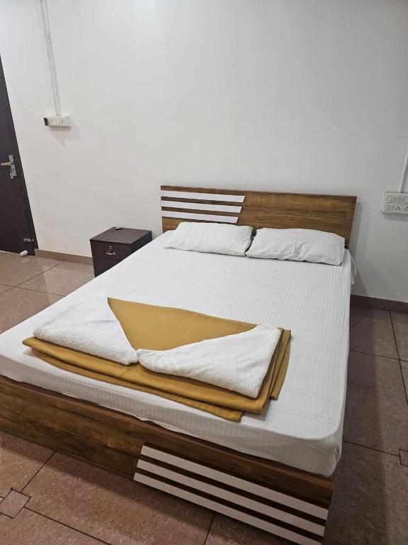 a large bed with white sheets and a wooden headboard at Relaxinn Dwaraka in Mānantoddy