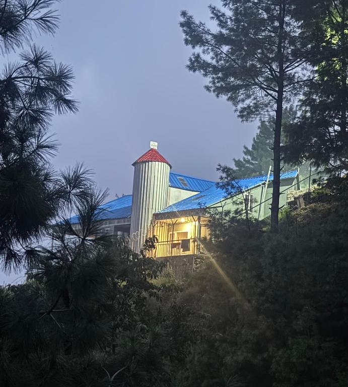 a barn with a silo and a building with trees at Casa Azul Mountain Resort in Nathia Gali