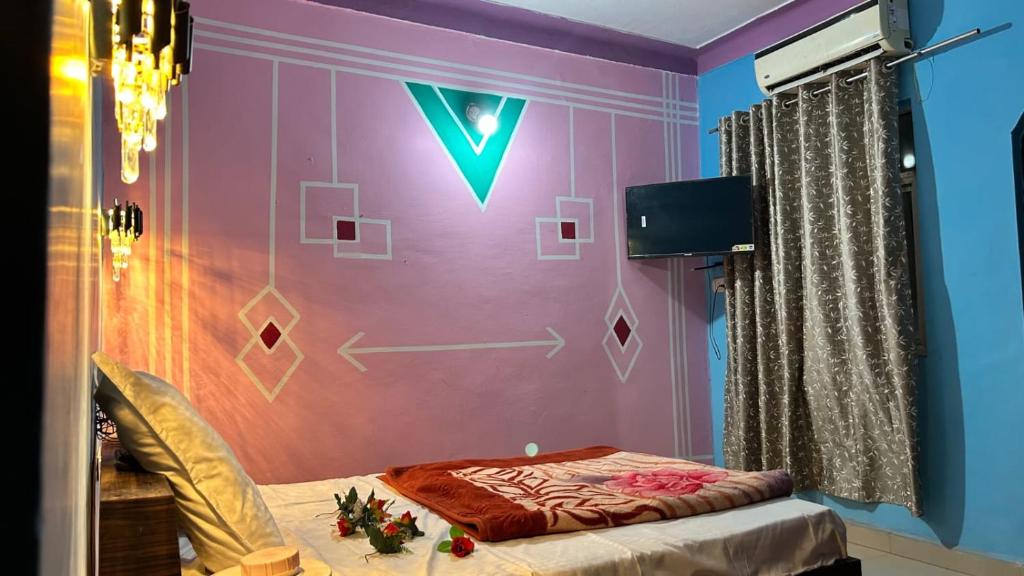 a room with a purple wall with a bed and a tv at RR palace in Pachmarhī