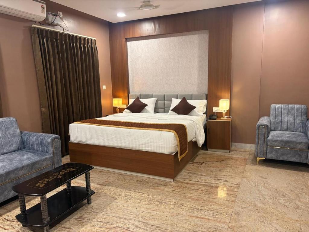 a bedroom with a large bed and two chairs at Raj Hussain Land Mark Hotel in Mayiladuthurai