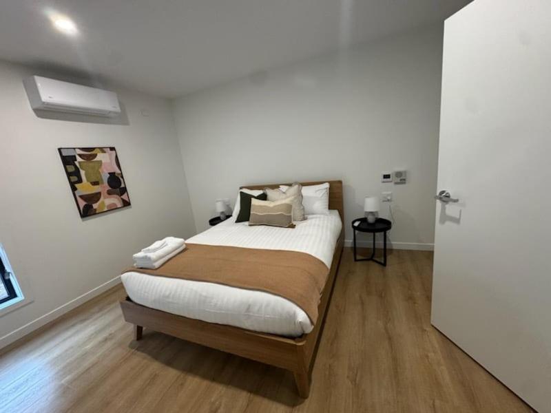 a bedroom with a bed with white walls and wooden floors at 3BR Haven in Stony Rise in Tugrah